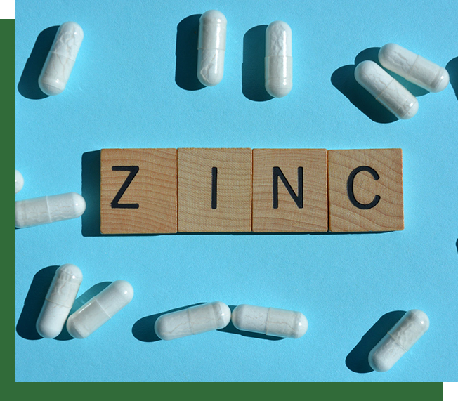 zinc-word-in-3d-wooden-alphabet-letters-surrounded-by-white-zinc-pill-capsules-isolated-on-blue-bac